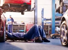 Garagiste qui répare une voiture dans un garage auto