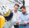 deux hommes regardant une tablette devant une machine industrielle